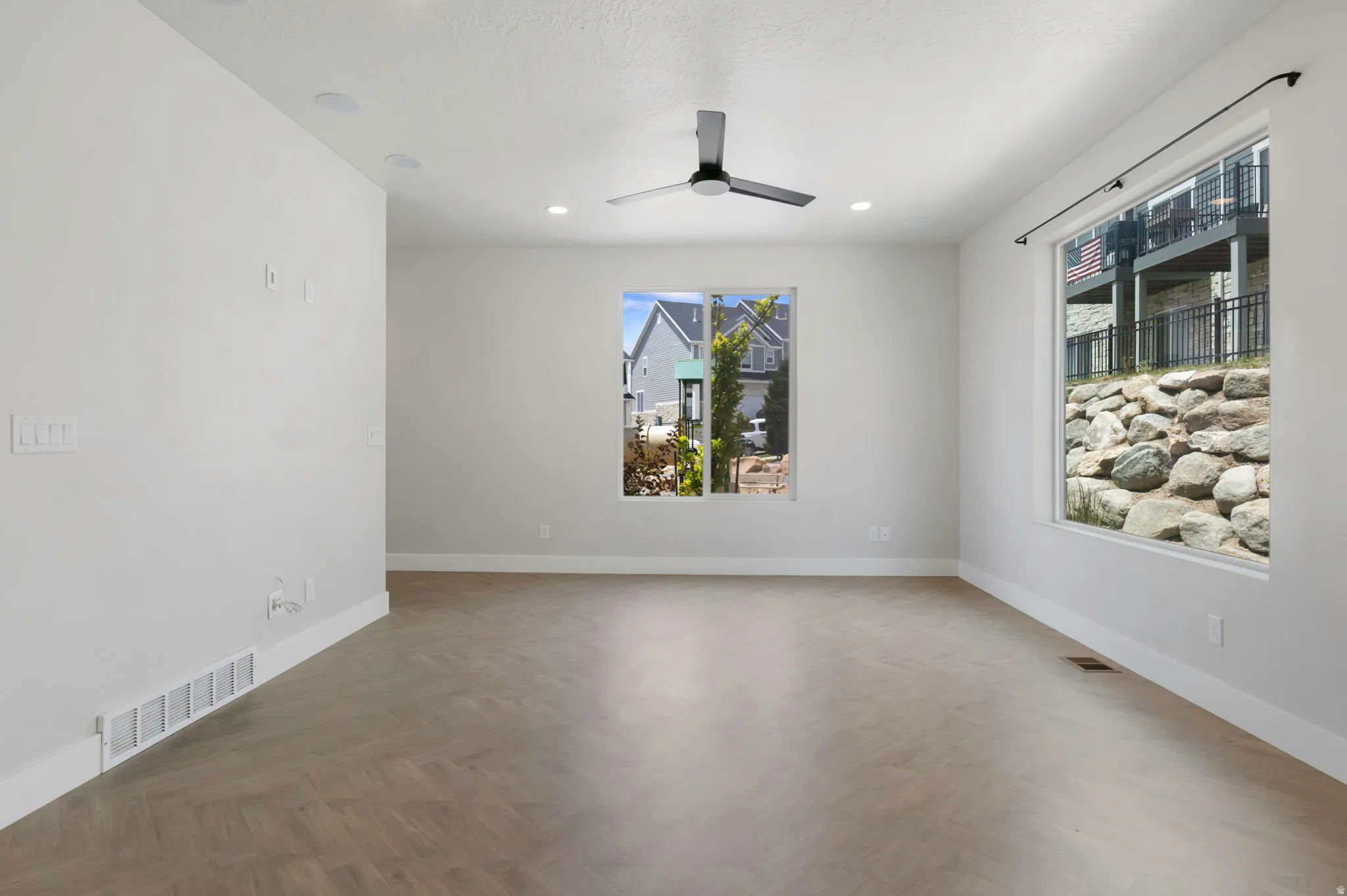 Spacious room featuring wood-finish flooring, recessed lighting, and a contemporary ceiling fan