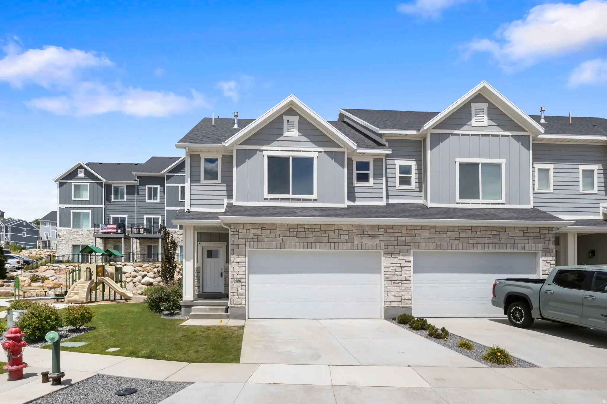 Contemporary townhome exterior featuring light gray siding and stone veneer accents