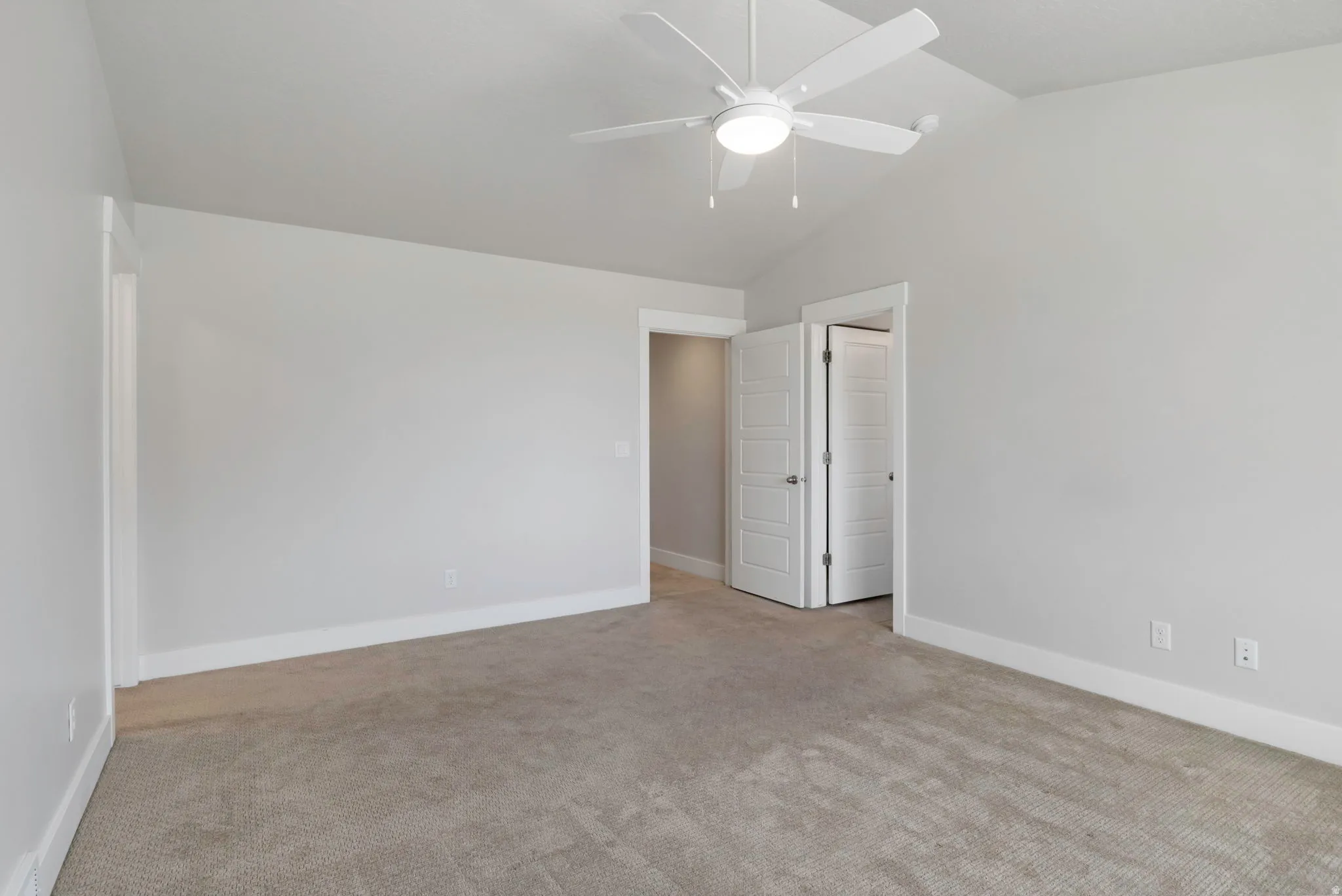 Interior room featuring vaulted ceilings, light gray wall paint, and neutral-toned carpeting