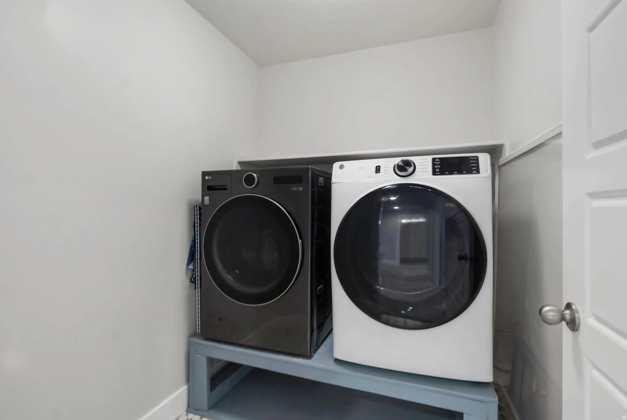 Dedicated laundry area featuring a built-in shelf, white walls, and a white interior door with a brushed nickel knob