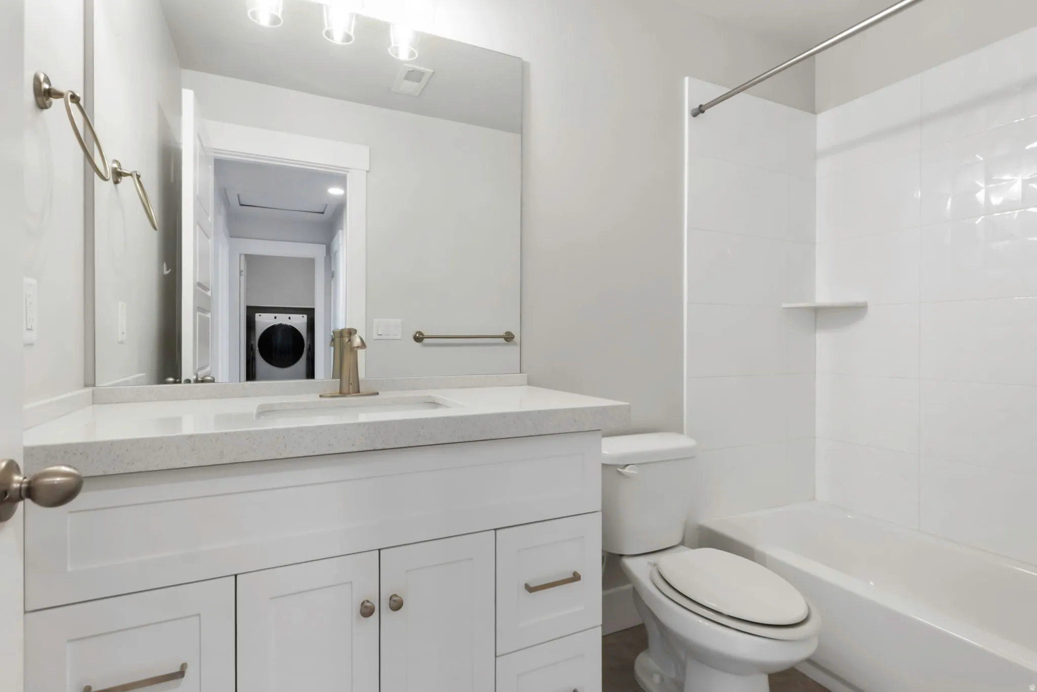Contemporary bathroom featuring a white vanity with shaker-style cabinetry, a speckled countertop, and a brushed nickel faucet