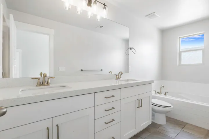 Bathroom with a double vanity featuring white shaker cabinetry, light-toned countertops, and brushed nickel hardware