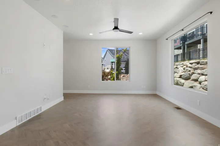 Spacious room featuring wood-finish flooring, recessed lighting, and a contemporary ceiling fan