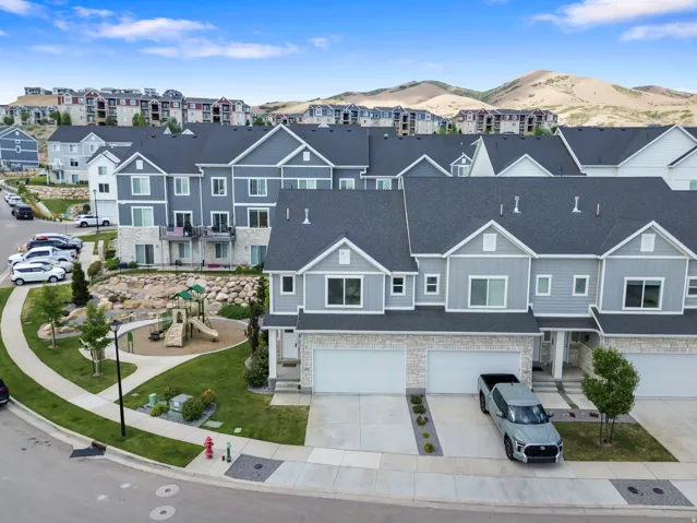 Contemporary townhome exterior featuring light gray siding, white trim, and stone veneer accents