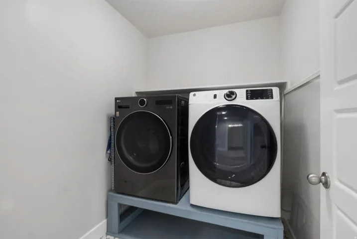Dedicated laundry area featuring a built-in shelf, white walls, and a white interior door with a brushed nickel knob