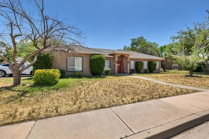 Single story home with stucco siding, a front yard, and a tiled roof
