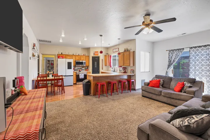 Living room featuring ceiling fan, a textured ceiling, and light carpet