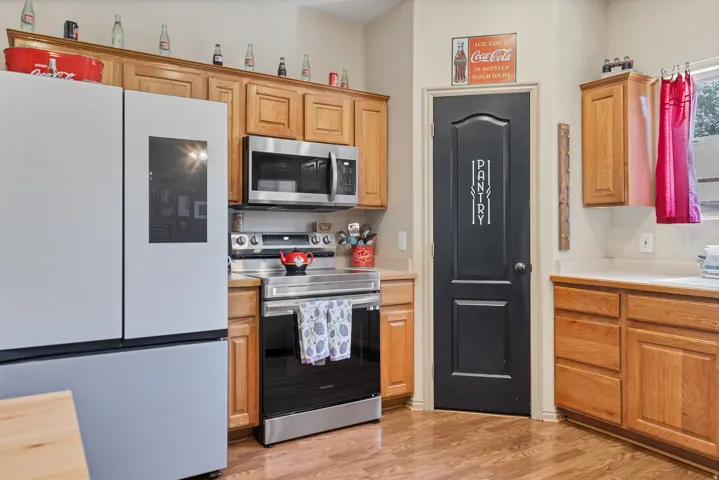 Kitchen with stainless steel appliances, light countertops, and light wood-style flooring