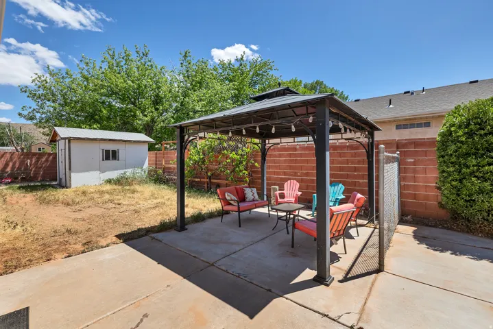 Fenced backyard with a patio, a gazebo, a storage shed, and an outdoor living space