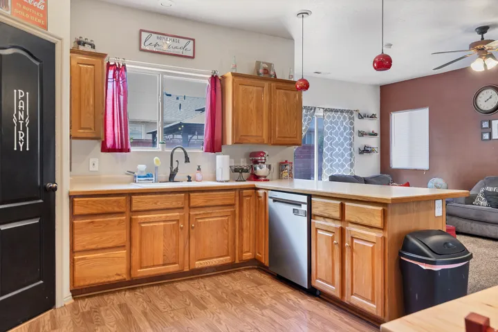 Kitchen with light countertops, a peninsula, light wood-style flooring, decorative light fixtures, and open floor plan