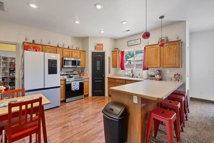 Kitchen featuring light countertops, stainless steel appliances, hanging light fixtures, a peninsula, and a breakfast bar