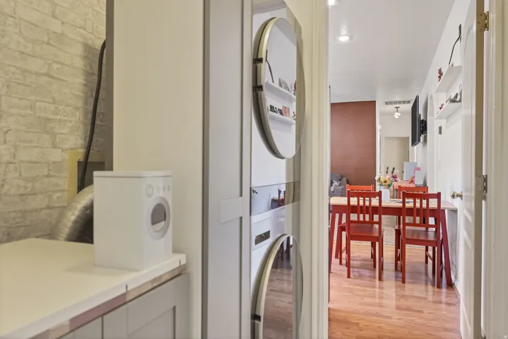 Laundry area with light wood-type flooring, stacked washer / drying machine, and recessed lighting