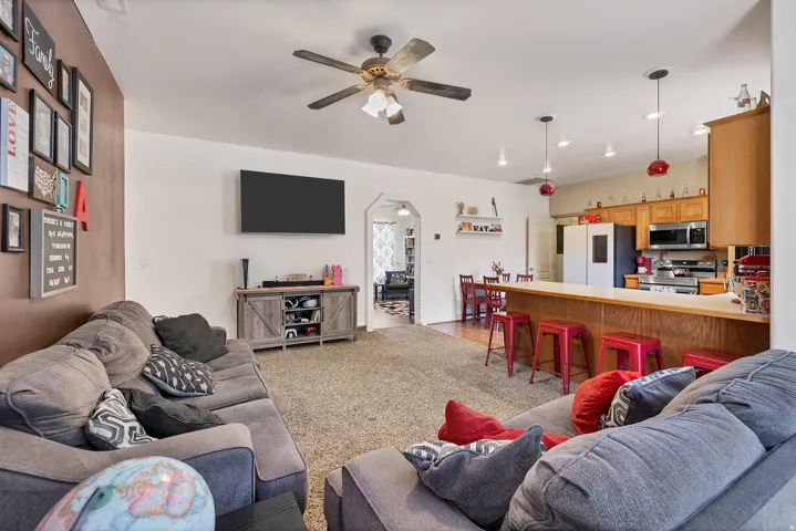 Living area featuring arched walkways, a ceiling fan, and light colored carpet