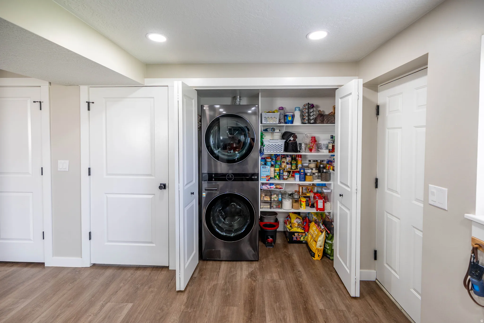 Laundry area with light wood-style floors, stacked washer and dryer, and recessed lighting