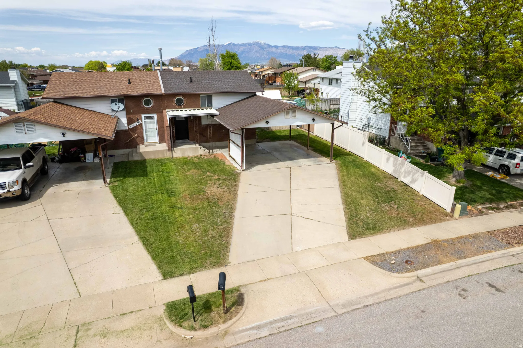 View of front of property featuring a residential view, a mountain view, a shingled roof, a driveway, and brick siding