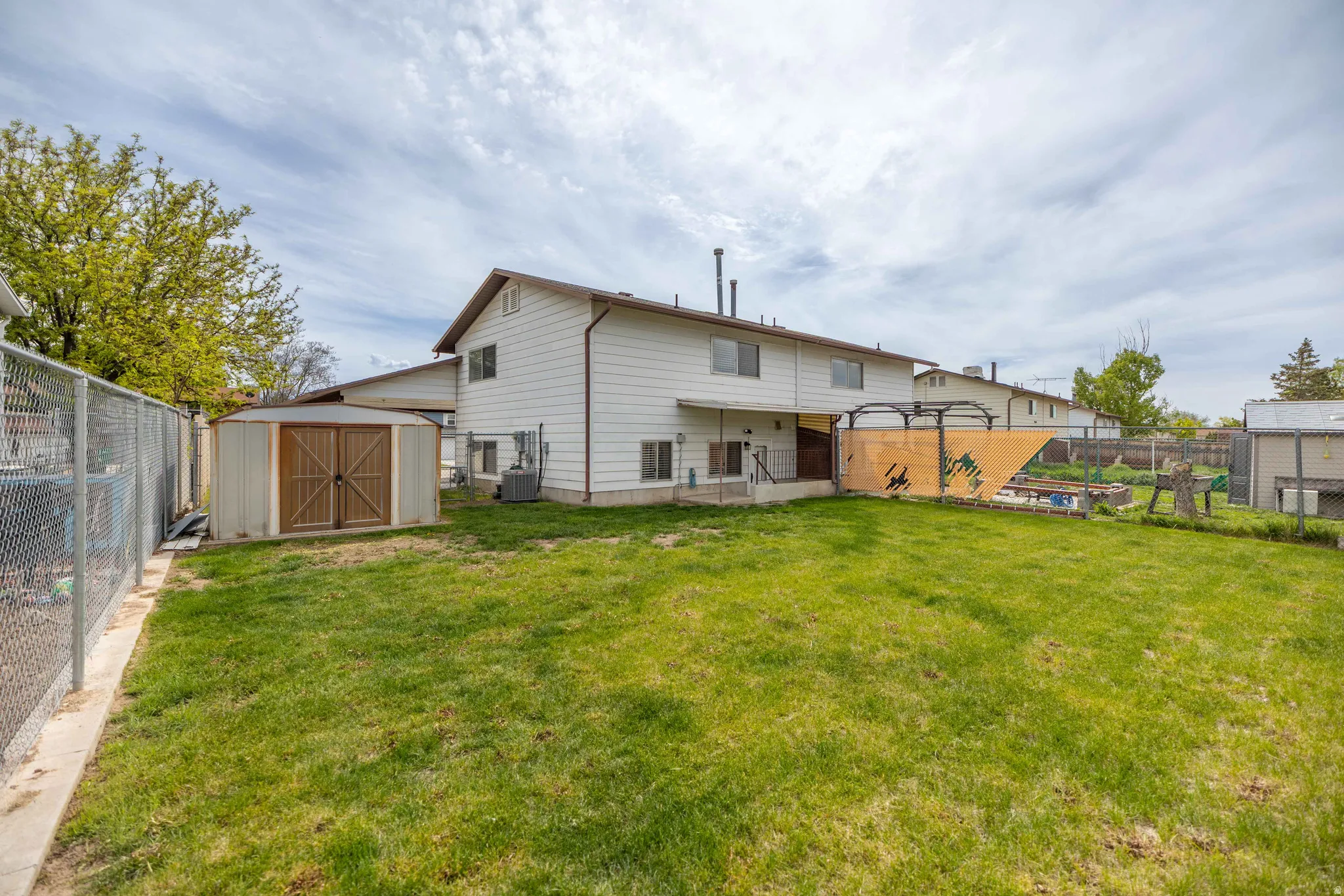 Back of house with a fenced backyard and a storage unit