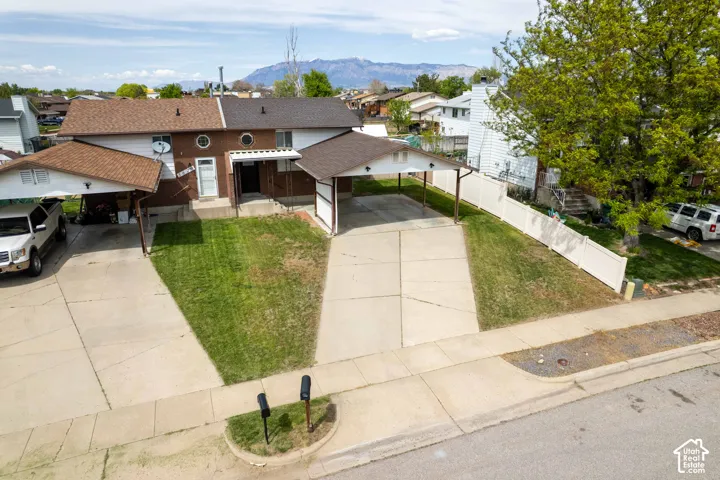 View of front of property featuring a residential view, a mountain view, a shingled roof, a driveway, and brick siding