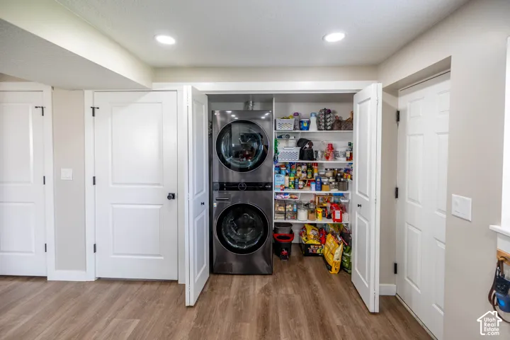 Laundry area with light wood-style floors, stacked washer and dryer, and recessed lighting