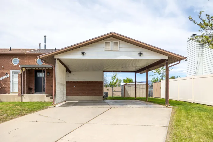 View of front facade with brick siding, driveway, a gate, and a carport