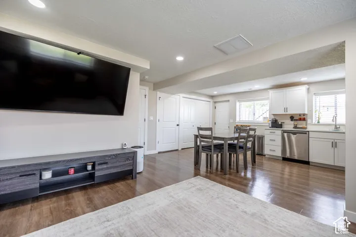 Living room featuring dark wood finished floors, a textured ceiling, and recessed lighting