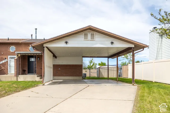 View of front facade with brick siding, driveway, a gate, and a carport