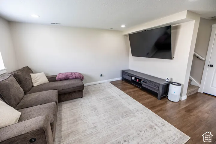 Living room with recessed lighting, dark wood-style floors, and a textured ceiling