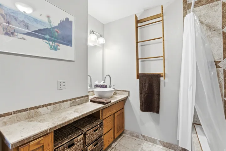 Bathroom vanity with a vessel sink, single-handle faucet, and overhead lighting