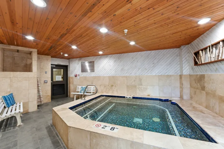 Indoor spa area featuring a tiled hot tub with perimeter grab rails