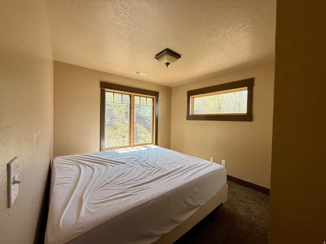 Bedroom with dark colored carpet and a textured ceiling