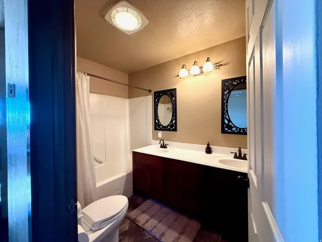 Bathroom with double vanity, a textured ceiling, and shower / bath combo