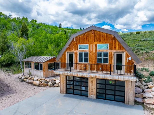View of front of detached garage with living space above, a balcony, a metal roof, concrete driveway, and a garage