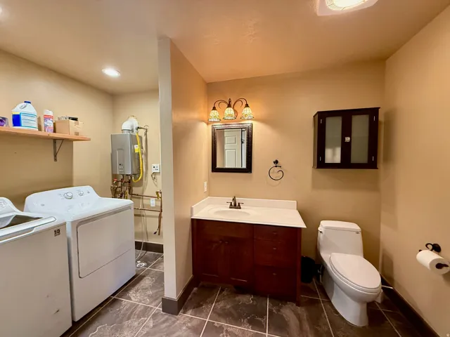 Bathroom featuring washer and dryer, vanity, and tankless water heater