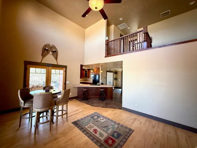 Dining space featuring light wood-style flooring, a ceiling fan, a high ceiling, and french doors