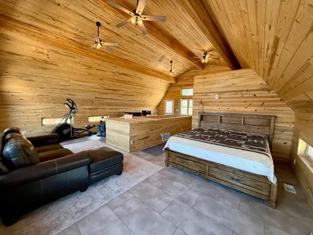 Bedroom with wood walls and a wood ceiling with exposed beams