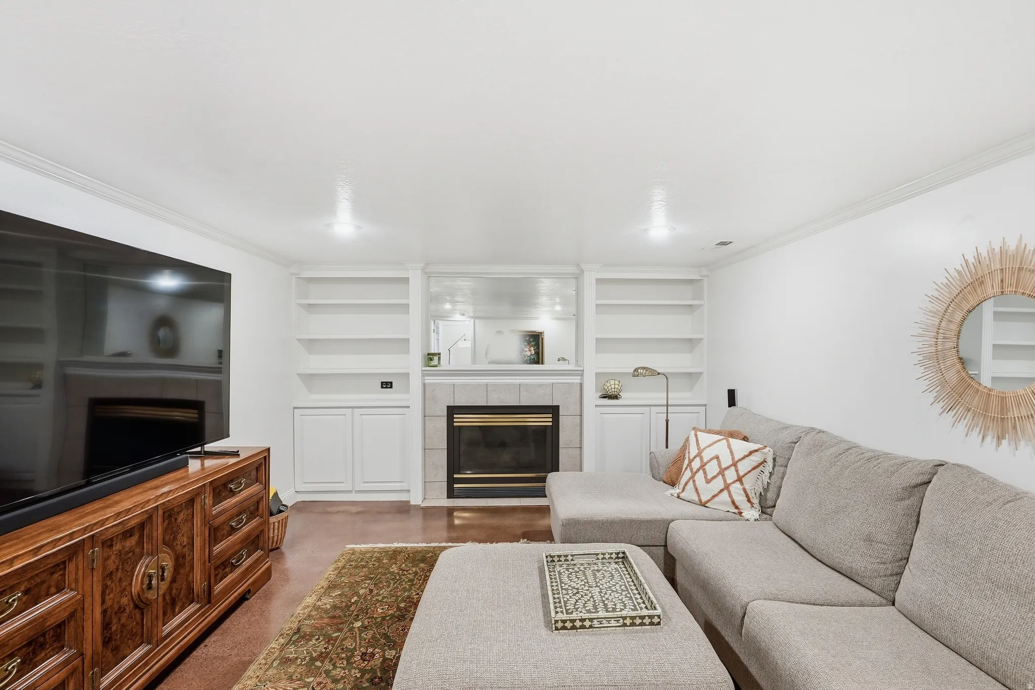 Built-in shelving and cabinetry flank a central fireplace with a tile surround and hearth