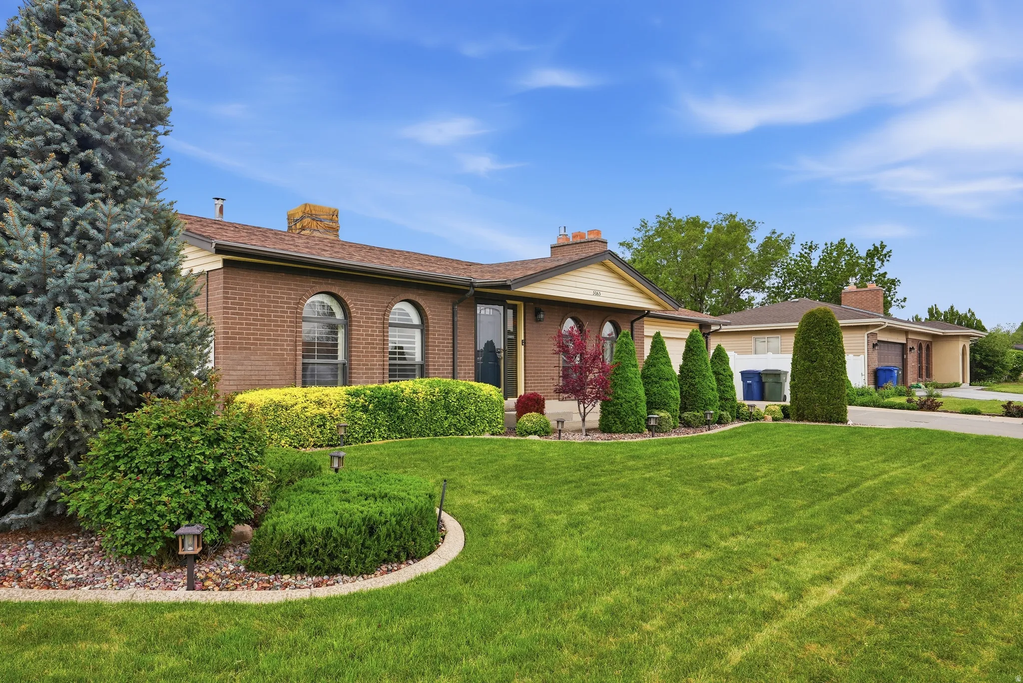 Brick exterior home featuring arched windows and a brown shingle roof