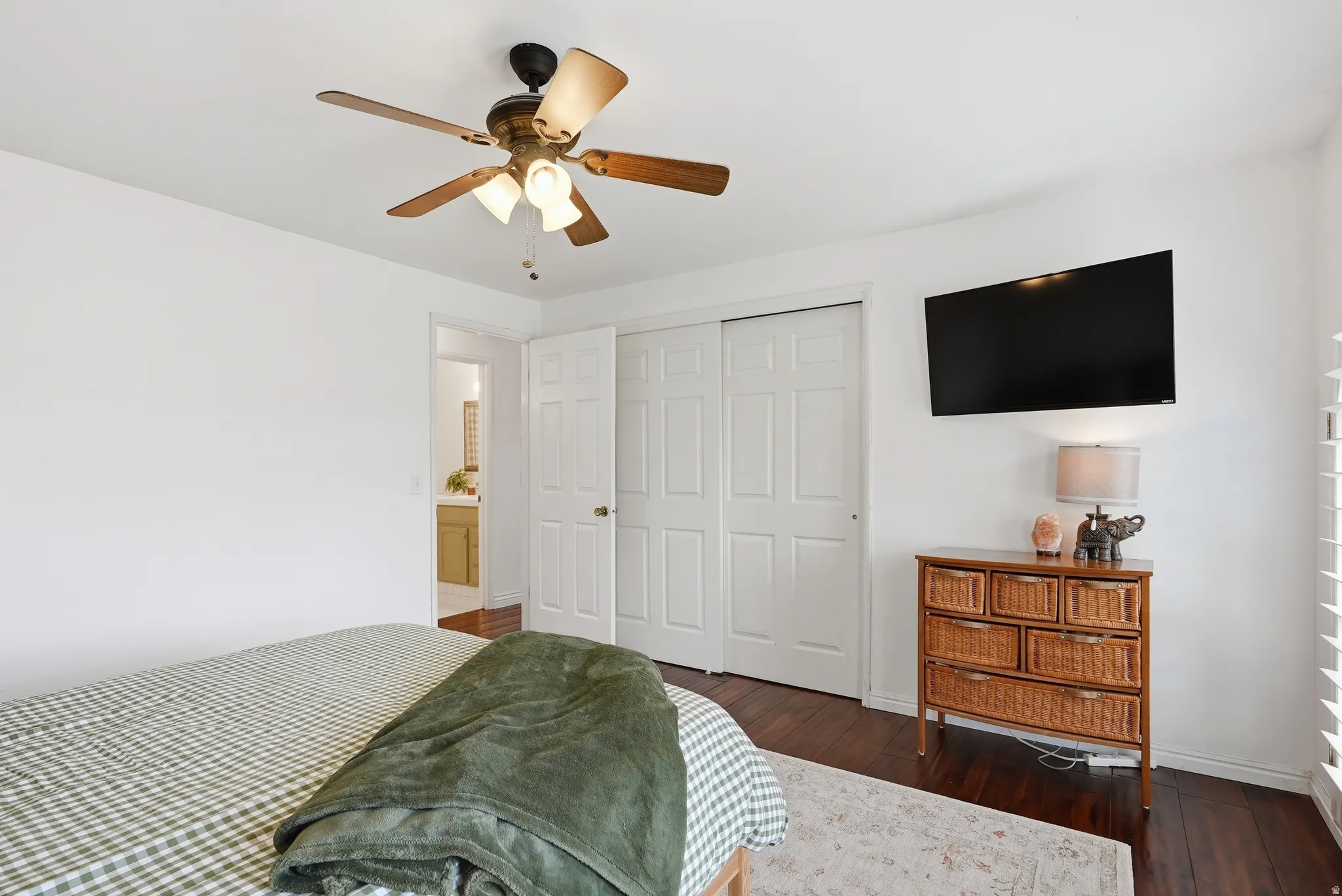 Bedroom featuring wood-finish flooring, a ceiling fan with integrated lighting, and white bi-fold closet doors