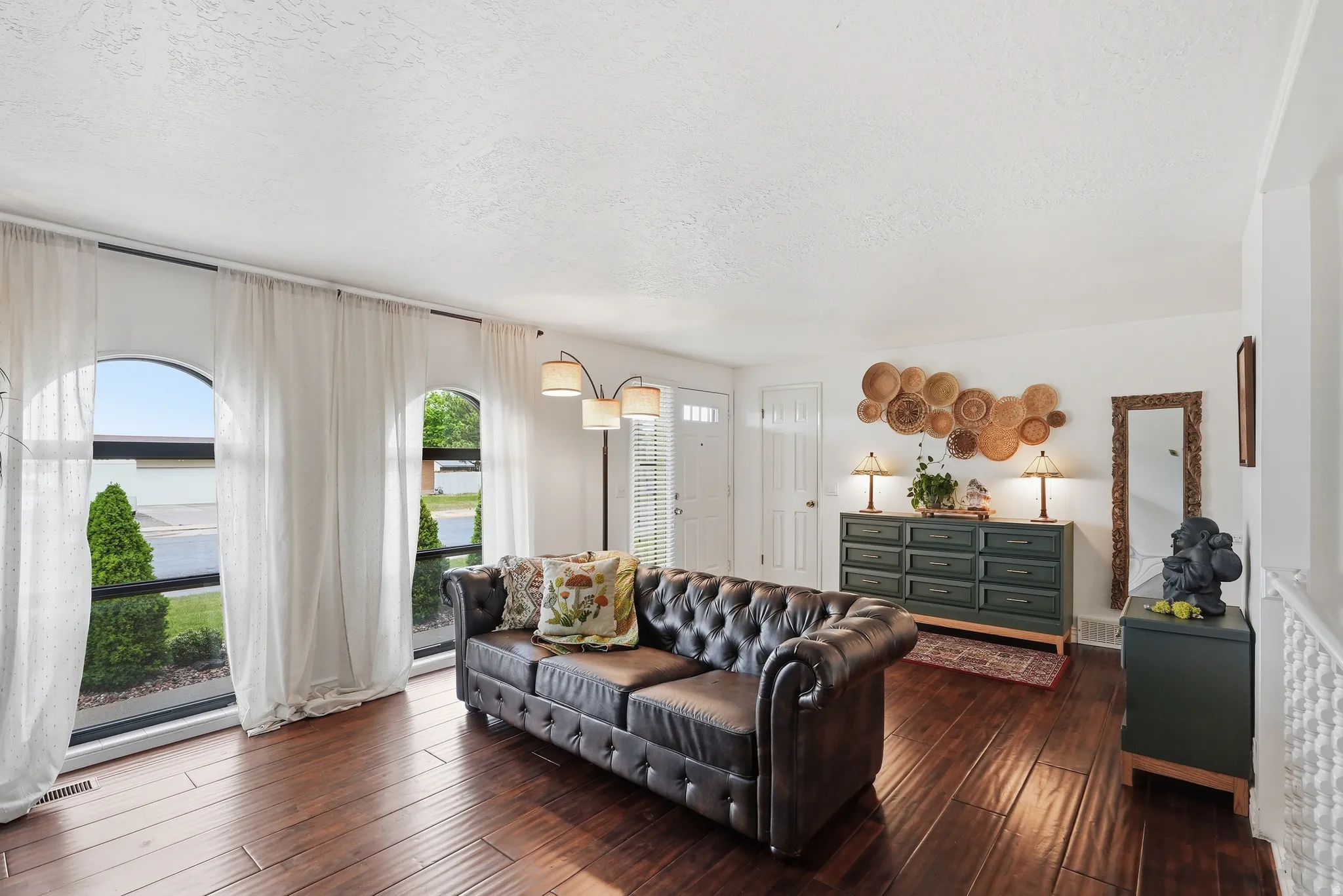 Living area with wood-finish flooring, white walls, and arched window features