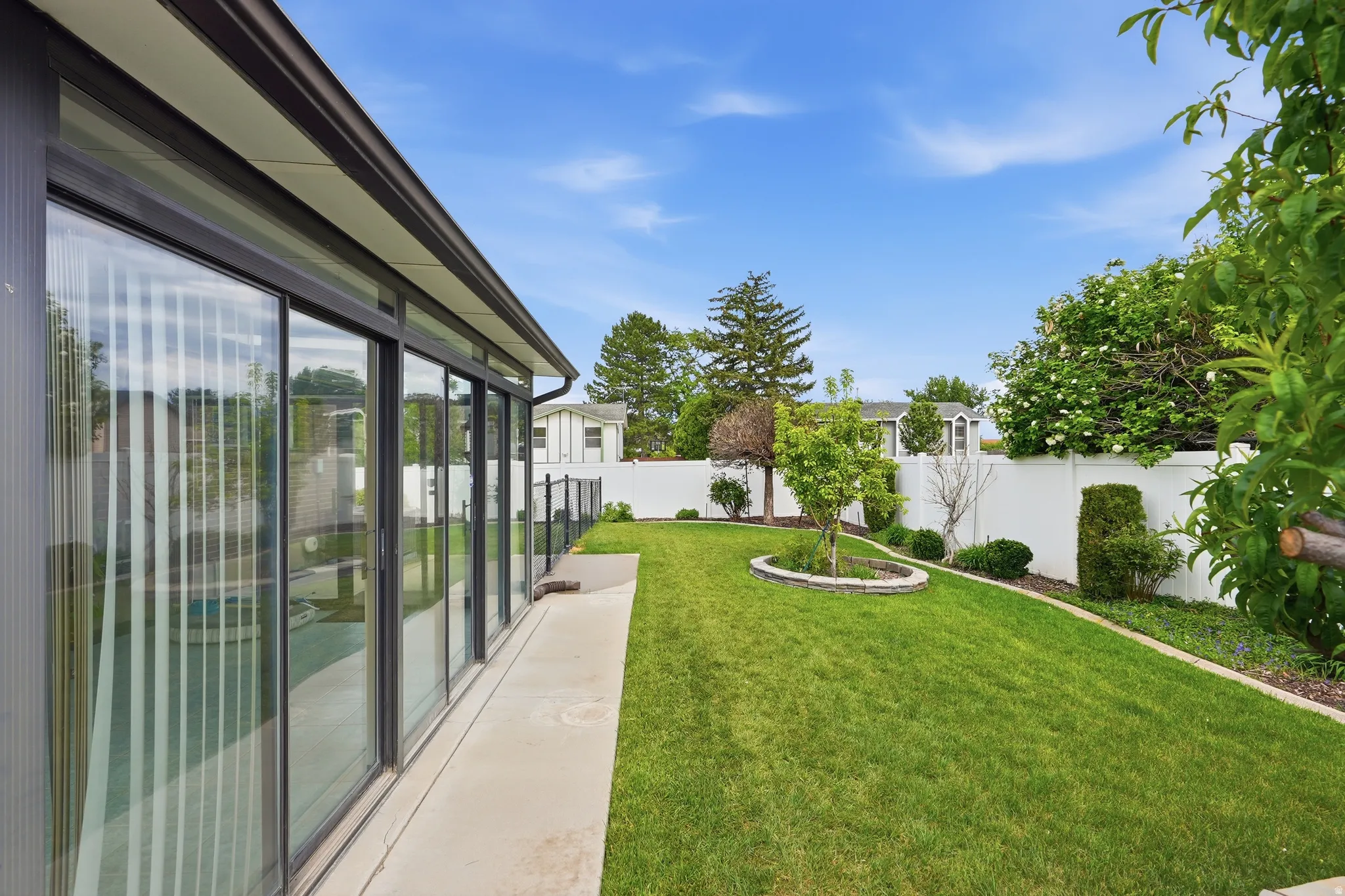 Expansive green lawn bordered by a white privacy fence and mature landscaping