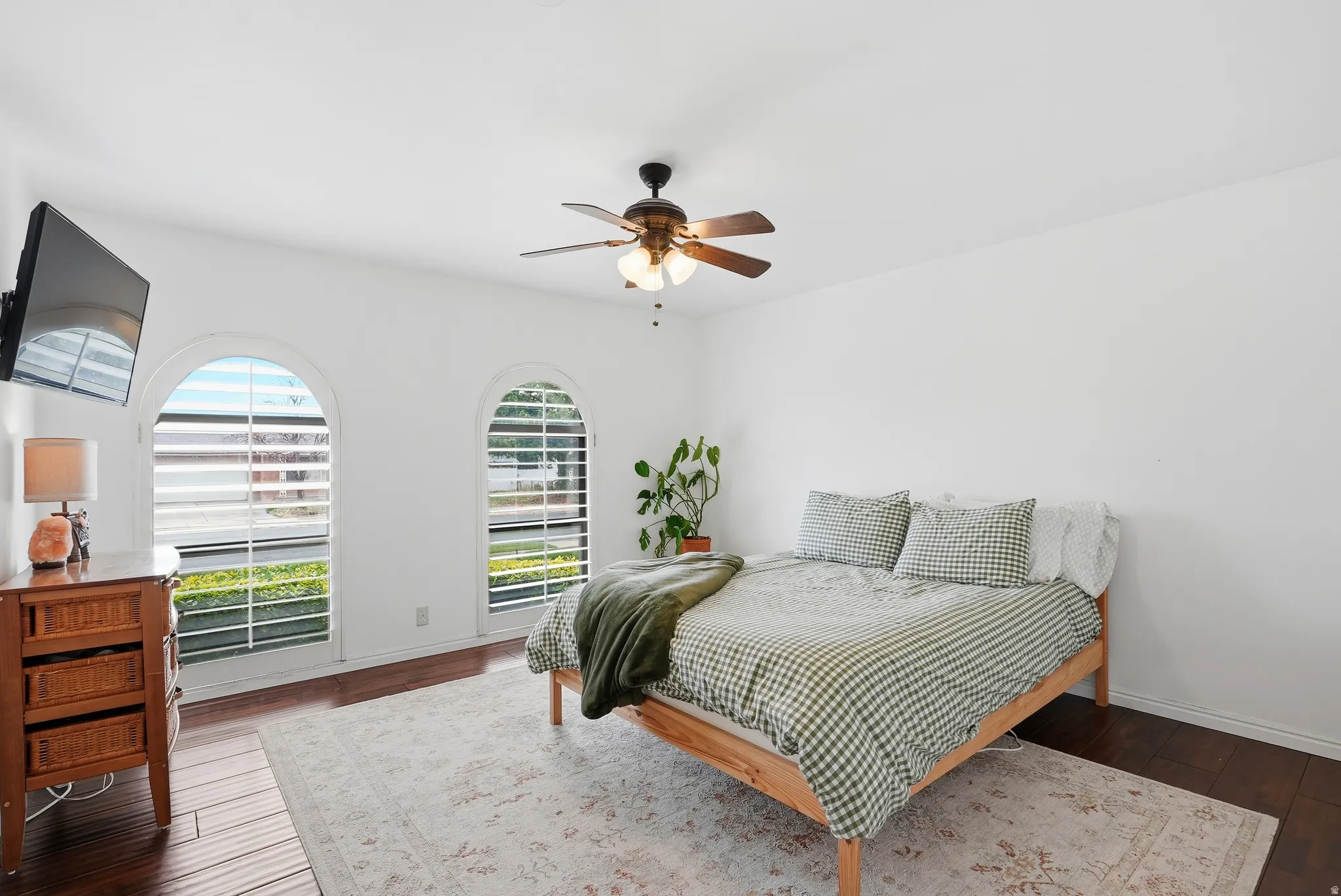 Bedroom with dark wood-finish flooring, white walls, and a ceiling fan
