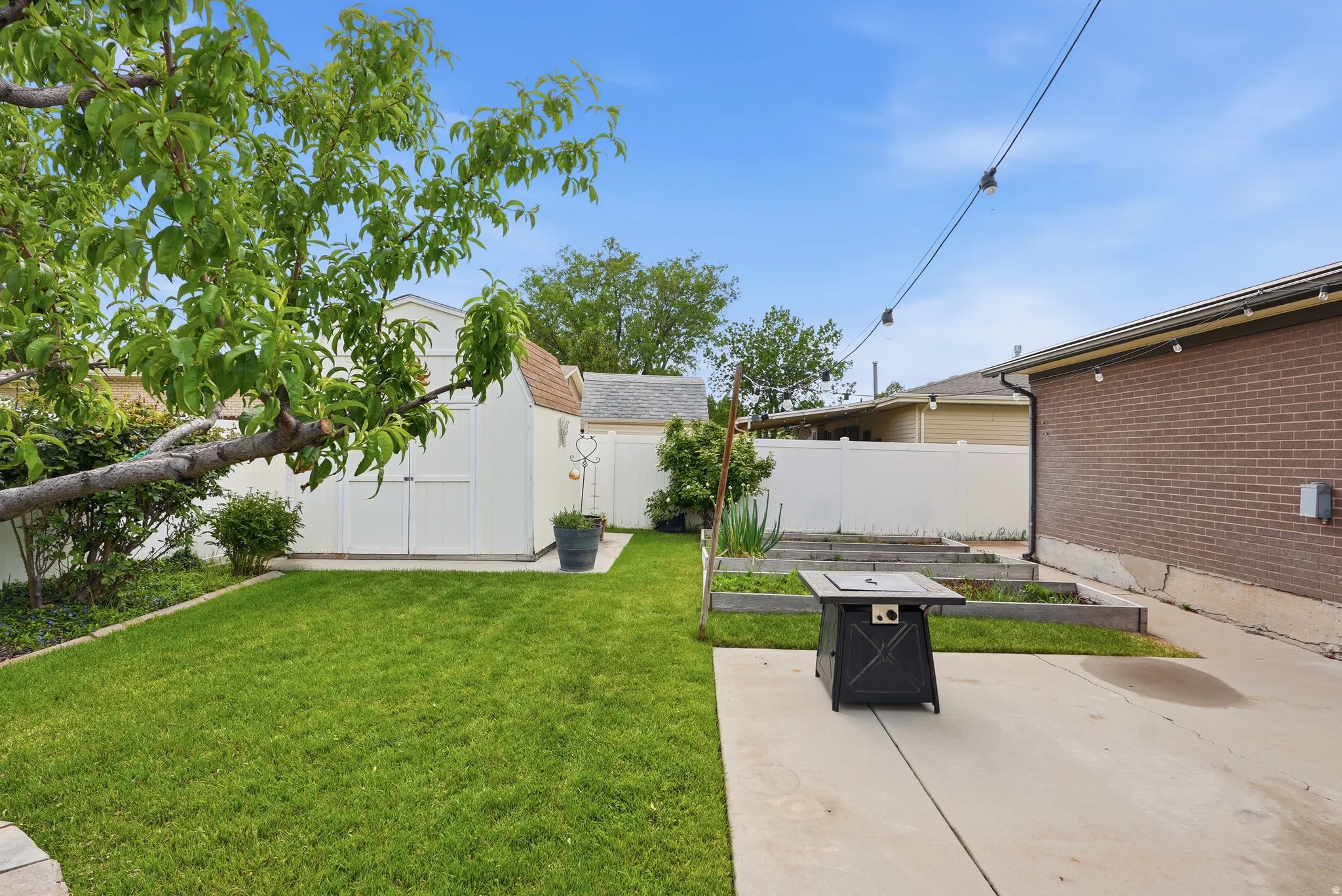Expansive backyard featuring a green lawn, concrete patio, and mature trees