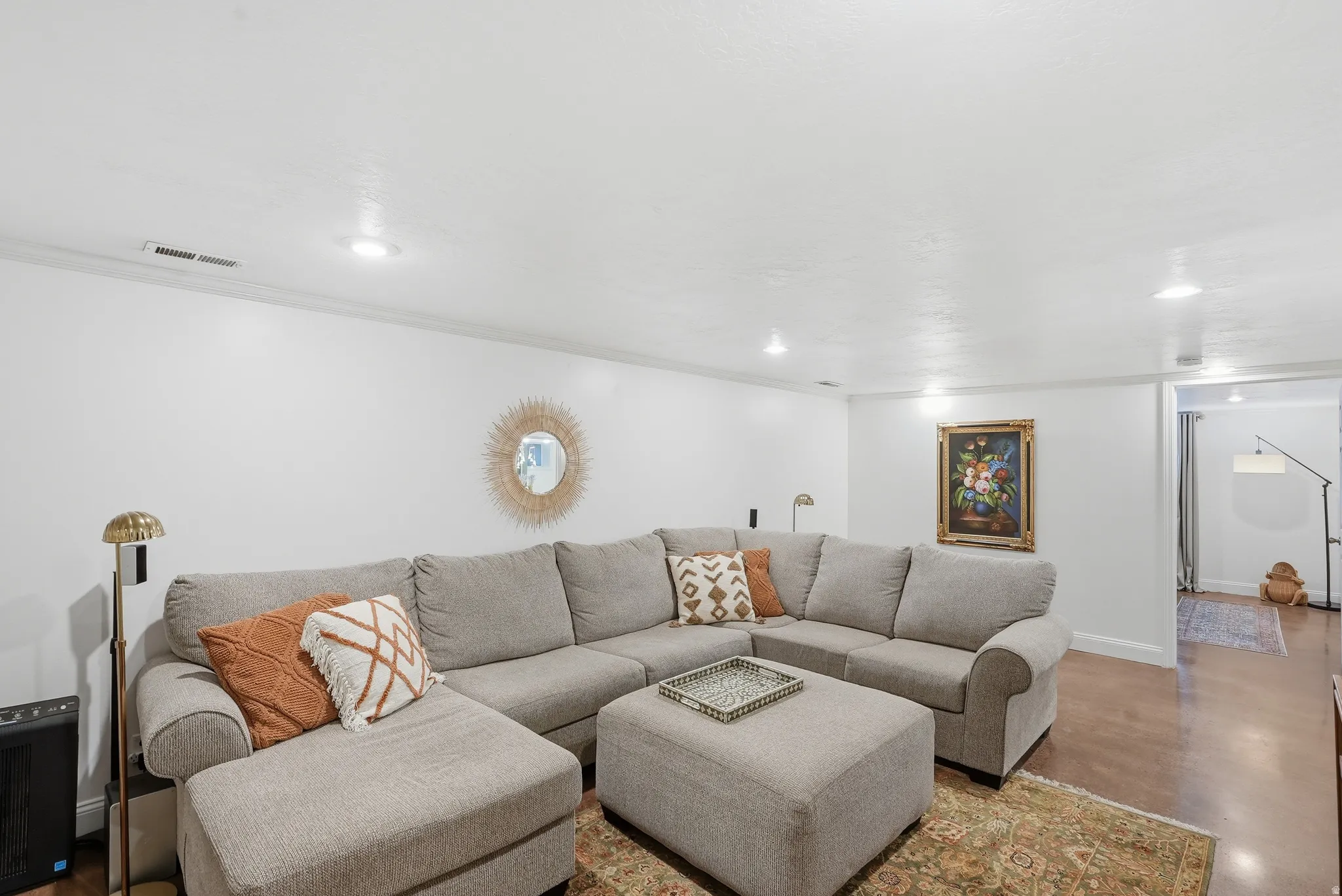 Spacious living area featuring light-colored walls, recessed ceiling lights, and crown molding