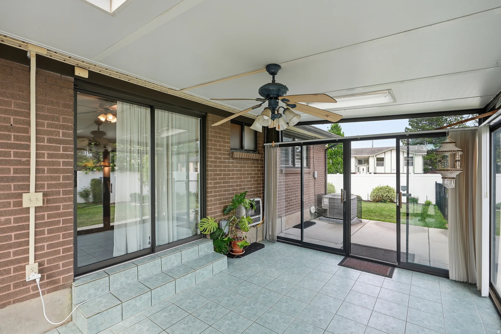 Enclosed patio featuring light blue floor tiling, an exposed brick wall, and multiple glass sliding doors