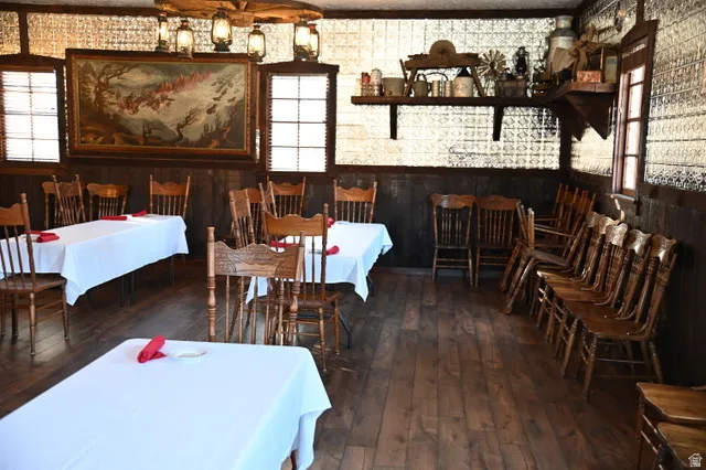 Spacious dining area featuring wood-finish flooring, dark wood paneling, and a unique pressed tin ceiling
