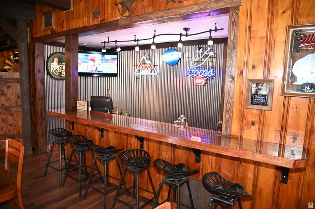 Custom bar area featuring rich wood-finish paneling, a glossy countertop, and corrugated metal wall accents