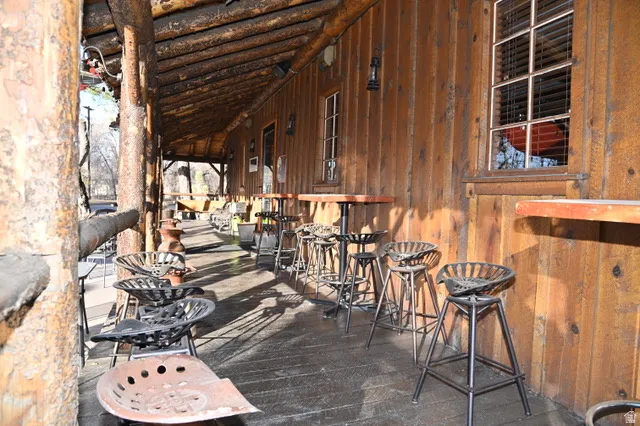 Covered porch with exposed log beam construction and wood paneling