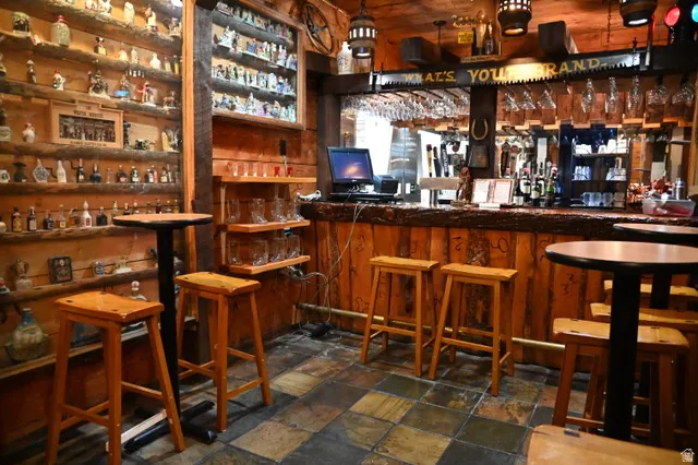 Rustic-themed entertainment space featuring a custom wood-plank bar with integrated shelving and overhead glass racks