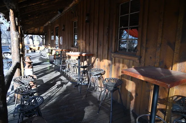 Expansive covered porch featuring a wood plank floor and a natural wood log support structure