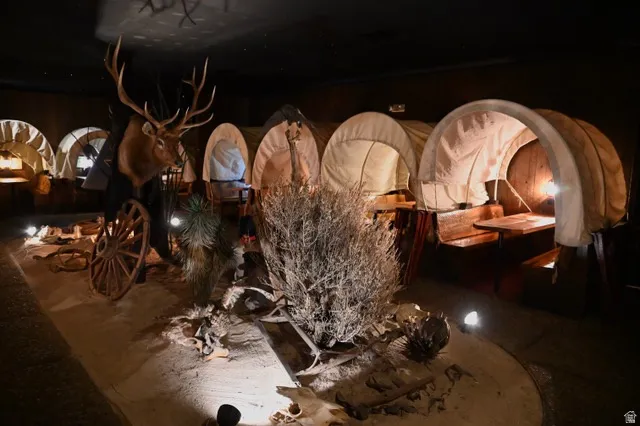 Themed interior space featuring multiple covered wagon structures, decorative flora, and a large mounted animal head