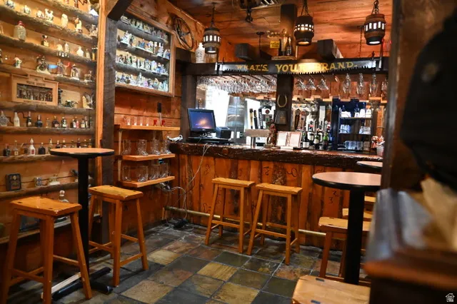 Custom wood-paneled bar area featuring a built-in bar, wood-finish flooring, and integrated shelving